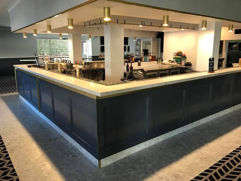 Commercial bar fit-out with navy panelling, marble top and brass trims