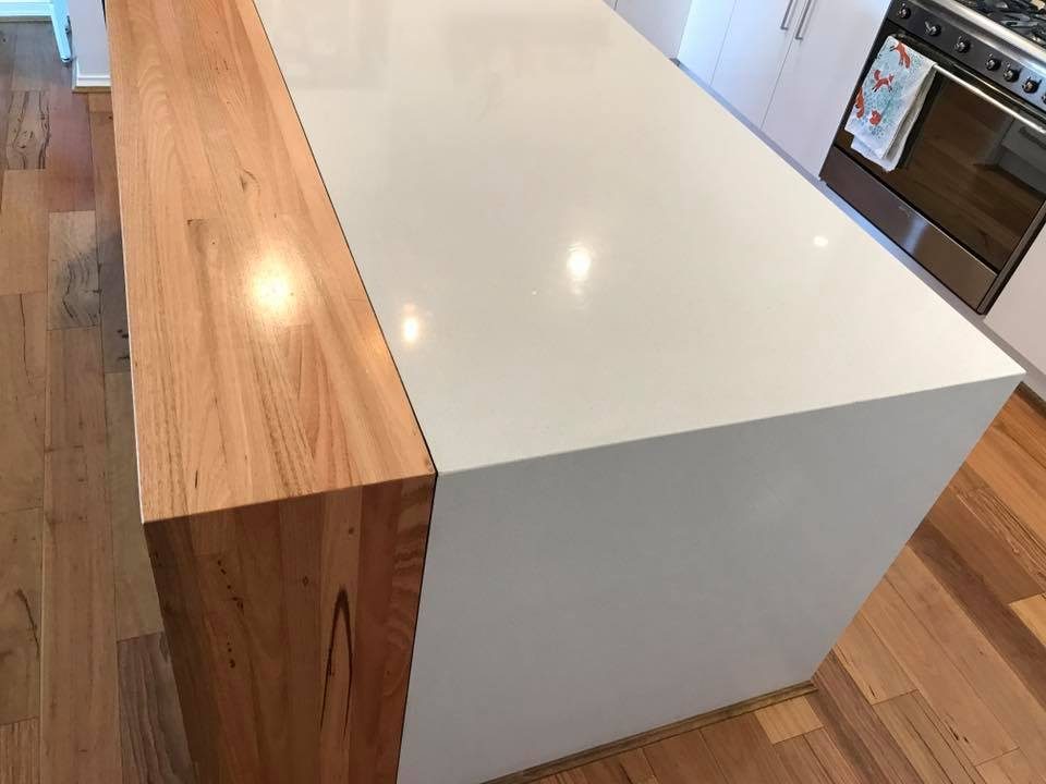 White stone island bench with solid timber waterfall side